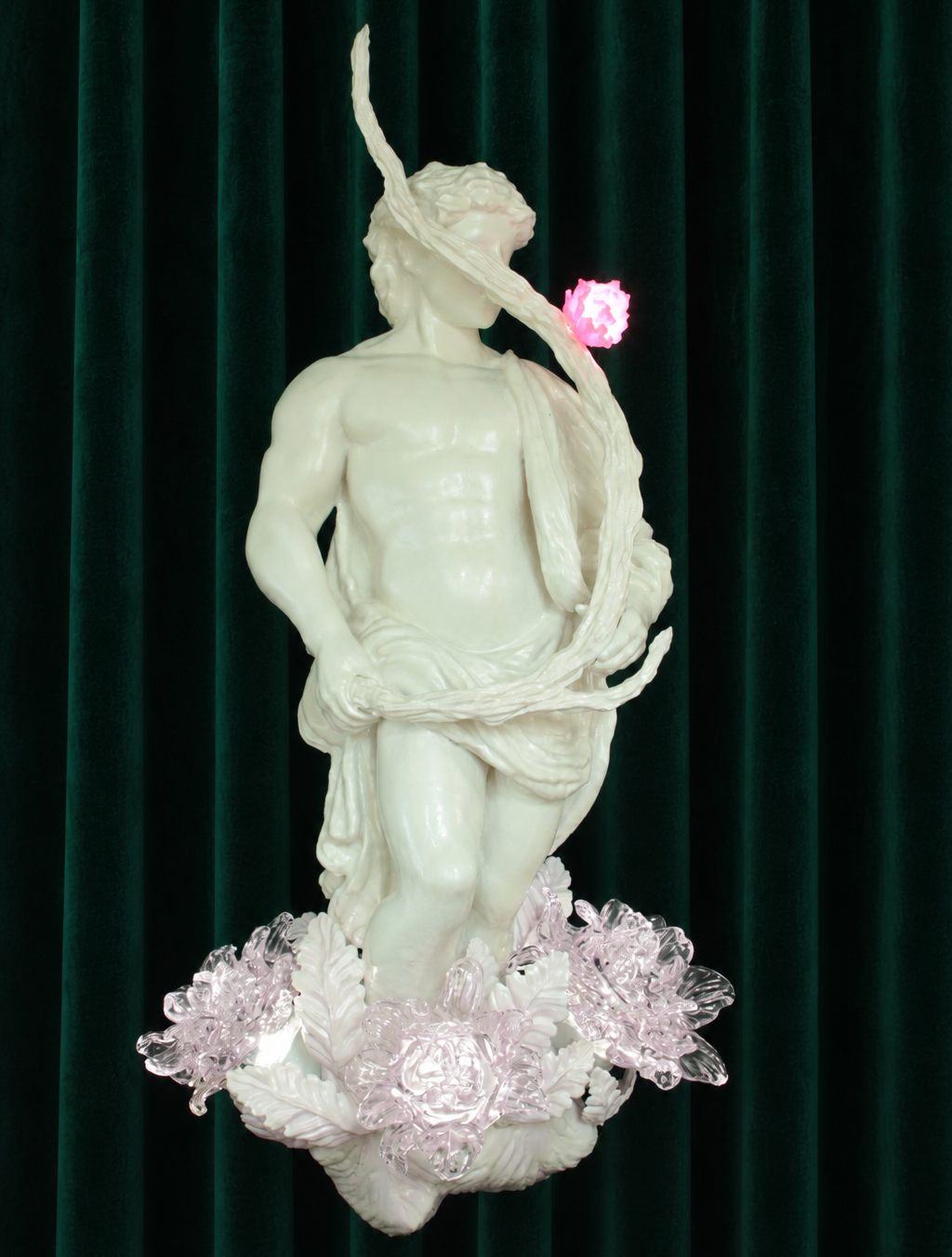 Stick Licker in the Flowers, 2026. Sculpture by Teemu Salonen. White figurative sculpture with translucent pink flowers against a dark green velvet backdrop.